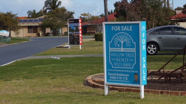 Two for sale signs on laws outside houses in Perth's south.