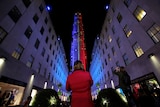People take pictures of 30 Rockefeller Plaza as it is lit in the colours of the Democratic and Republican parties.