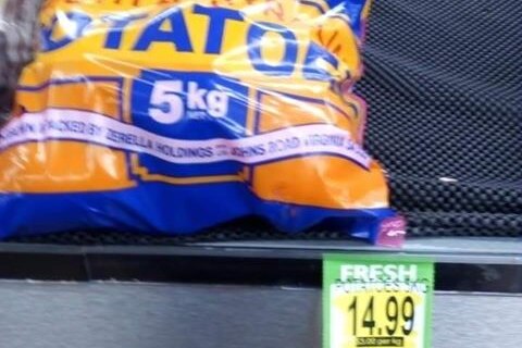 A bag of potatoes with a $14.99 price tag sits on a shelf.
