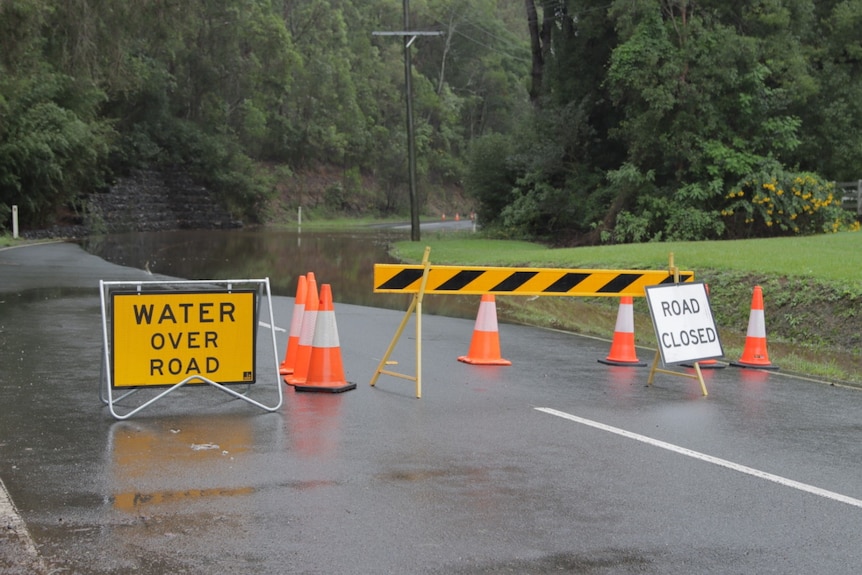 Water over road at Gap Creek Road in Kenmore Hills and road closed signs with cones.