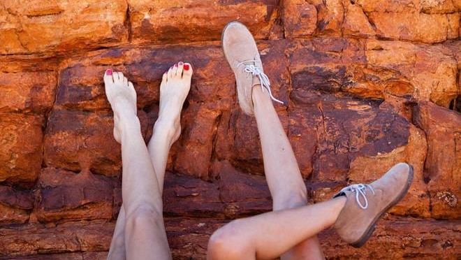 Two sets of legs on red rocks.