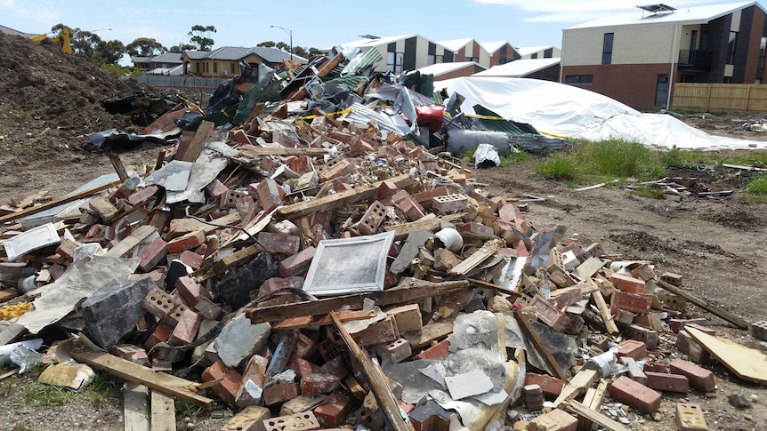 A pile of rubbish in a disused site surrounded by houses.