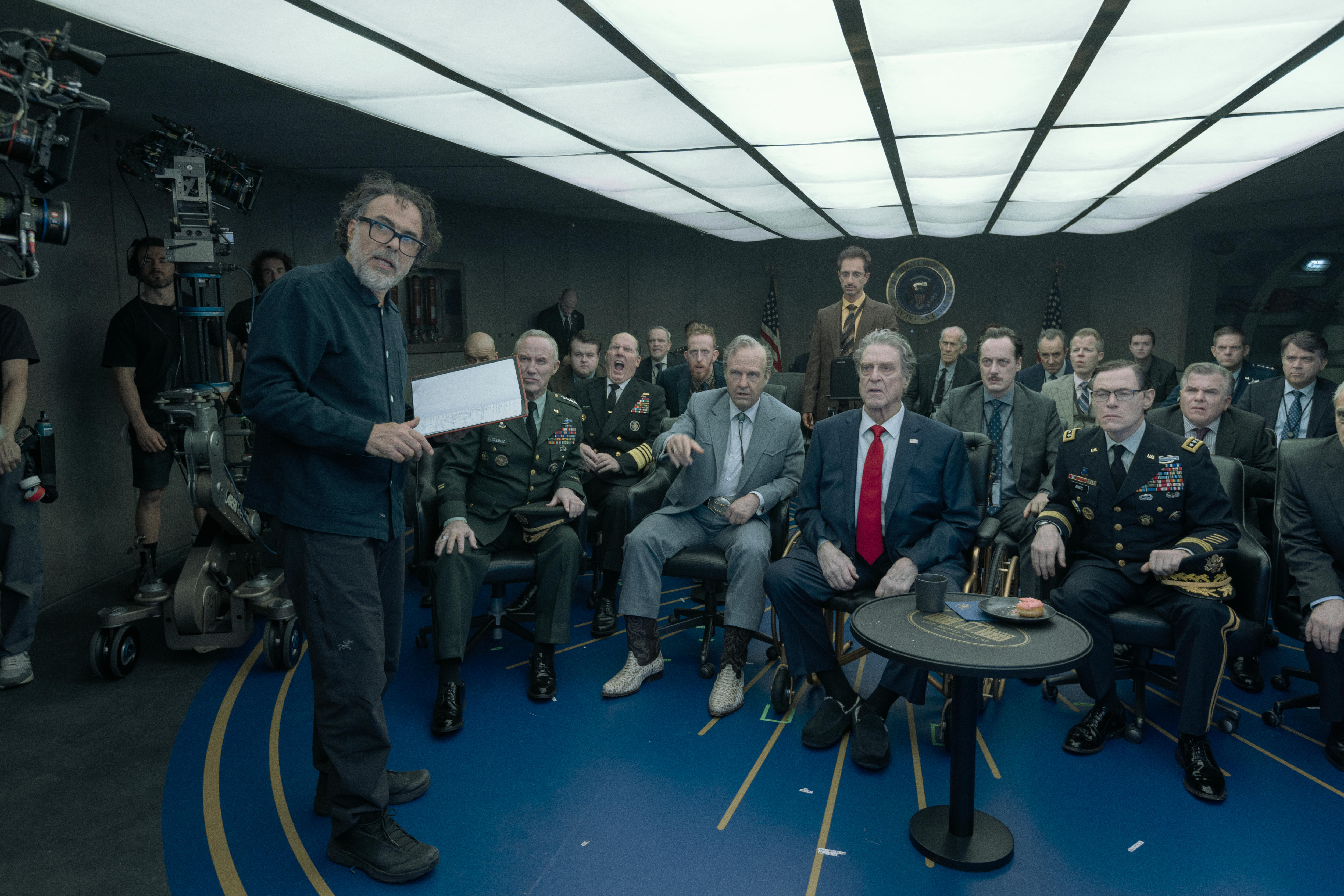 Alejandro G Iñárritu stands with notes in hand in front of a crowd of seated actors.