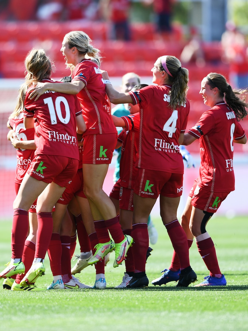 Soccer players wearing red jump and hug each other after a goal