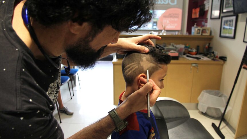 A barber shaves the Jets symbol into a little boy's head