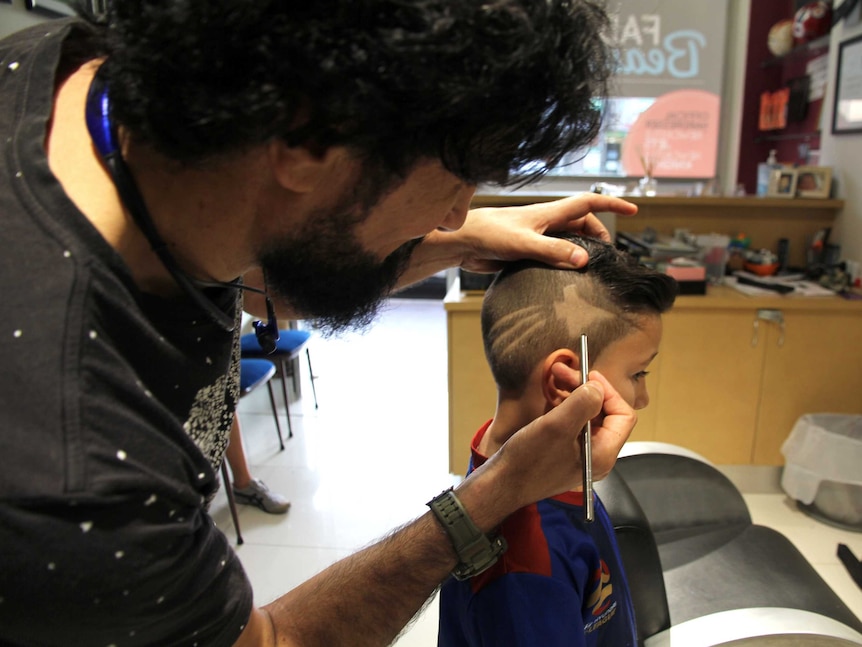 A barber shaves the Jets symbol into a little boy's head