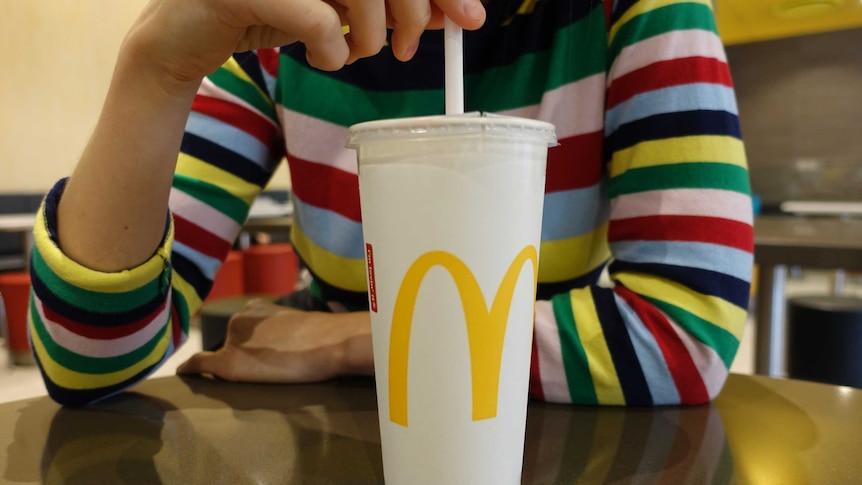 A young woman drinking a McDonald's thickshake