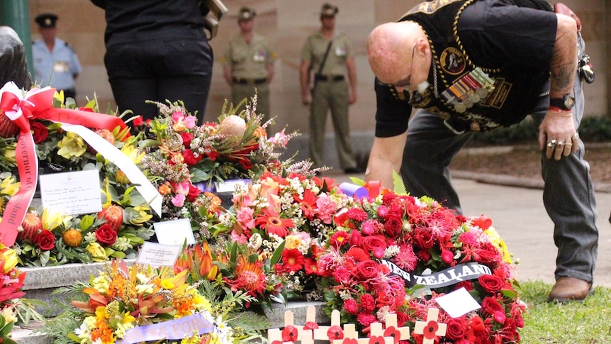 A man bends over a pile of wreaths.