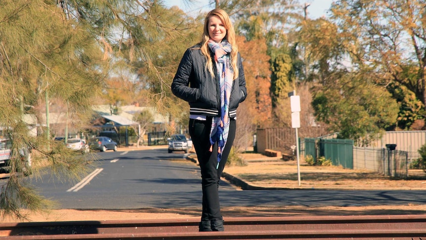 Historian Simone Taylor is pictured on a railway track overlooking a suburban street in Dubbo, NSW.