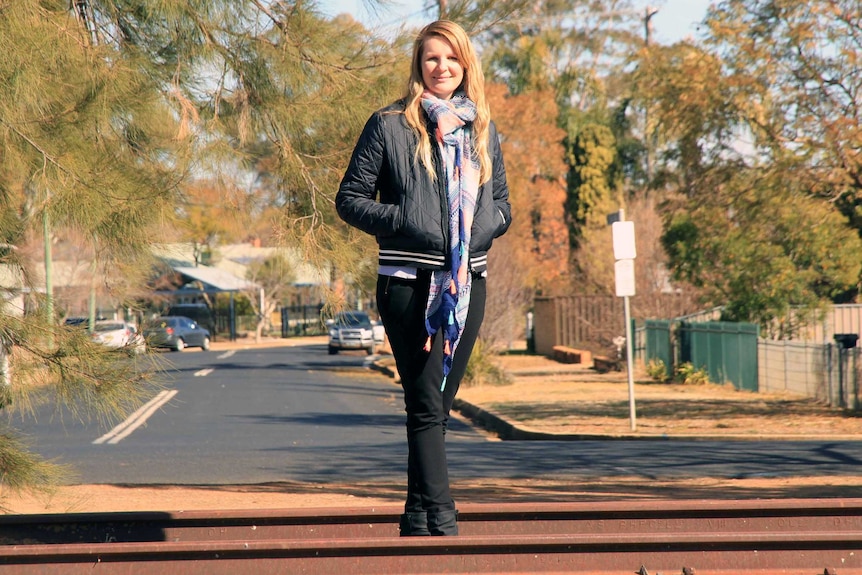 Historian Simone Taylor is pictured on a railway track overlooking a suburban street in Dubbo, NSW.