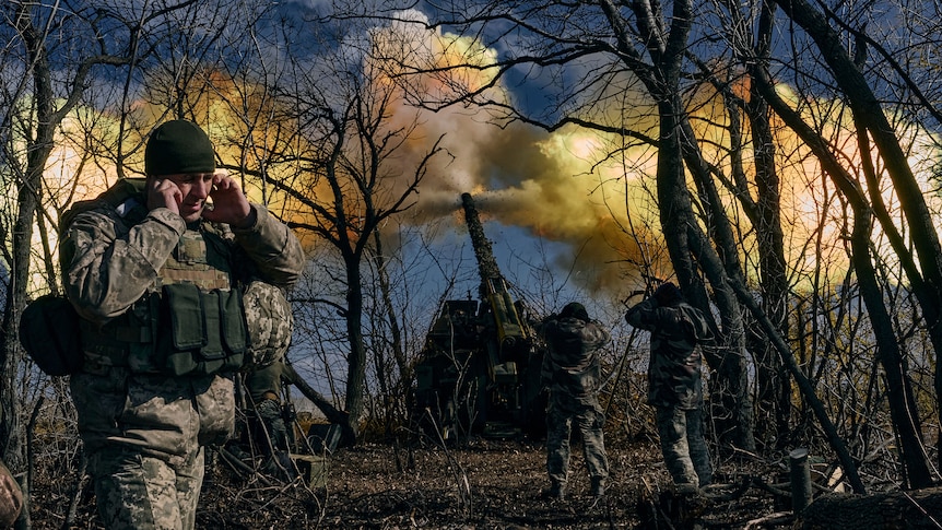 Yellow smoke fills the air as Ukrainian soldiers fire a self-propelled howitzer towards Russian positions.