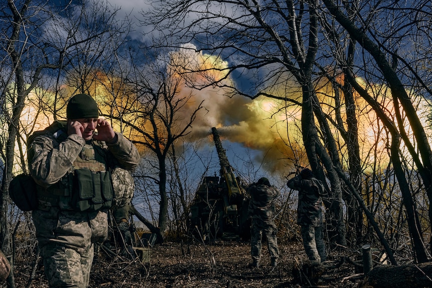 Yellow smoke fills the air as Ukrainian soldiers fire a self-propelled howitzer towards Russian positions.