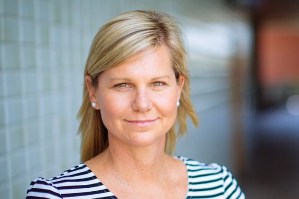 woman with blonde hair and hack and white shirt smiles at camera.