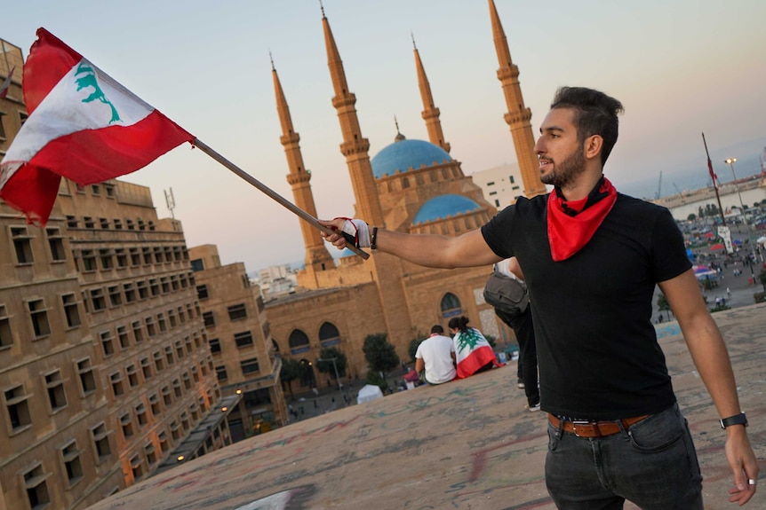 A young man waves a flag on a rooftop in Beirut