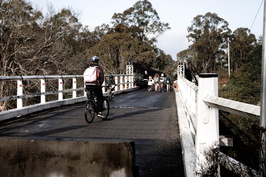 Kids and an adult on pushbike across a bridge that is closed to cars