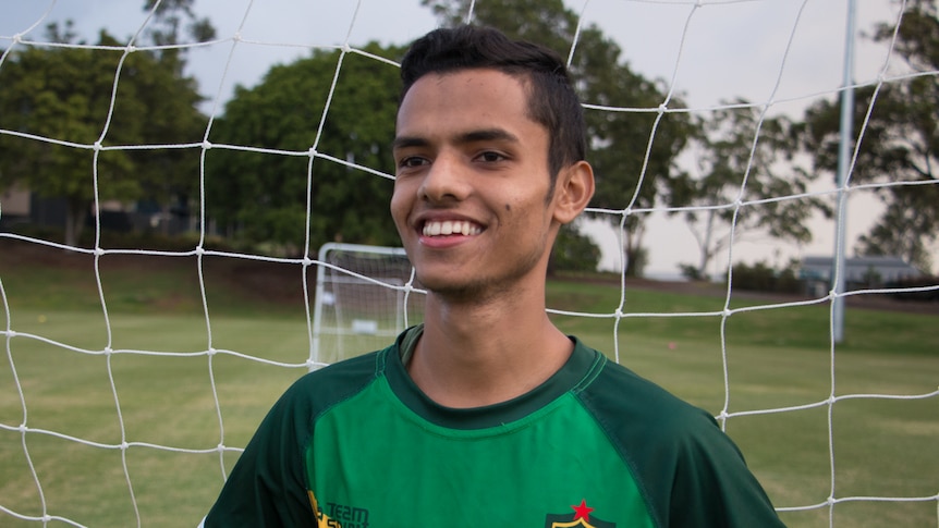 Young boy standing in front of a soccer net.