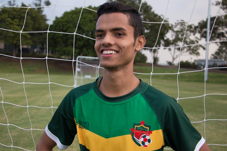 Young boy standing in front of a soccer net.