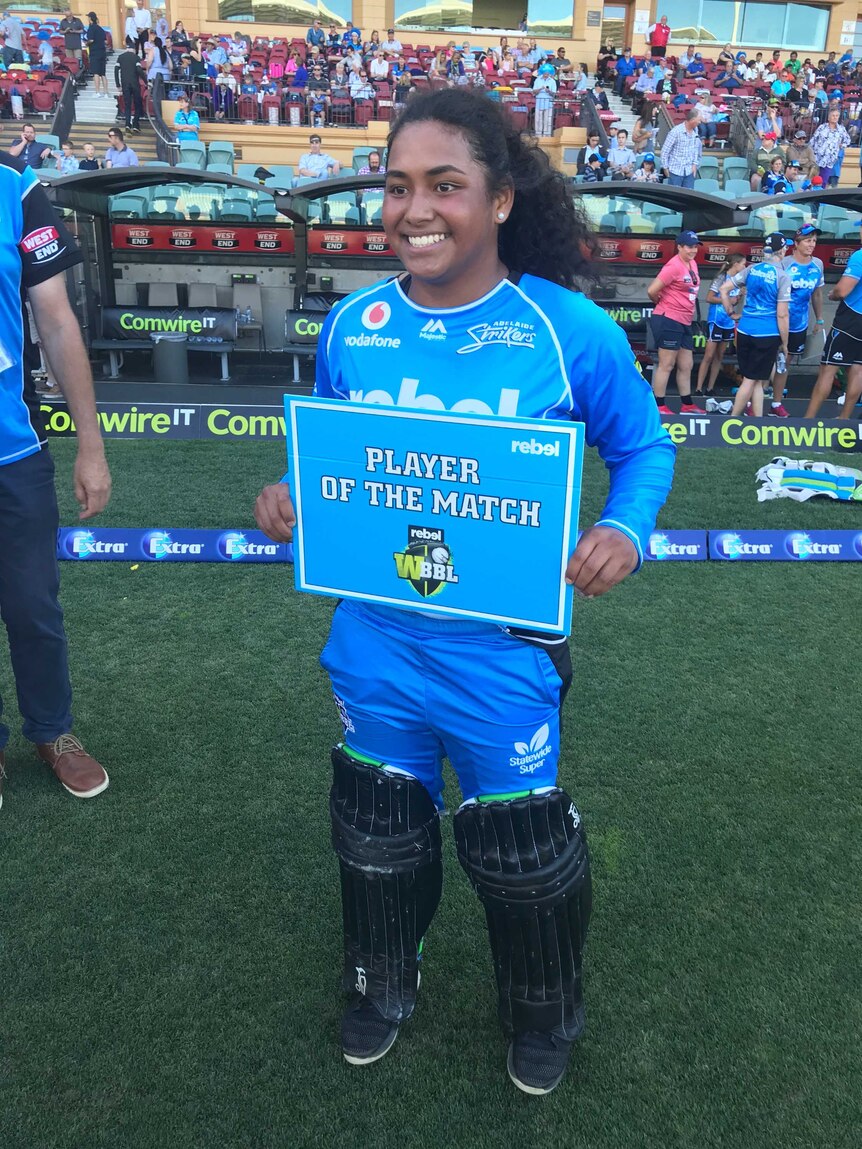 Woman stands with player of the match sign