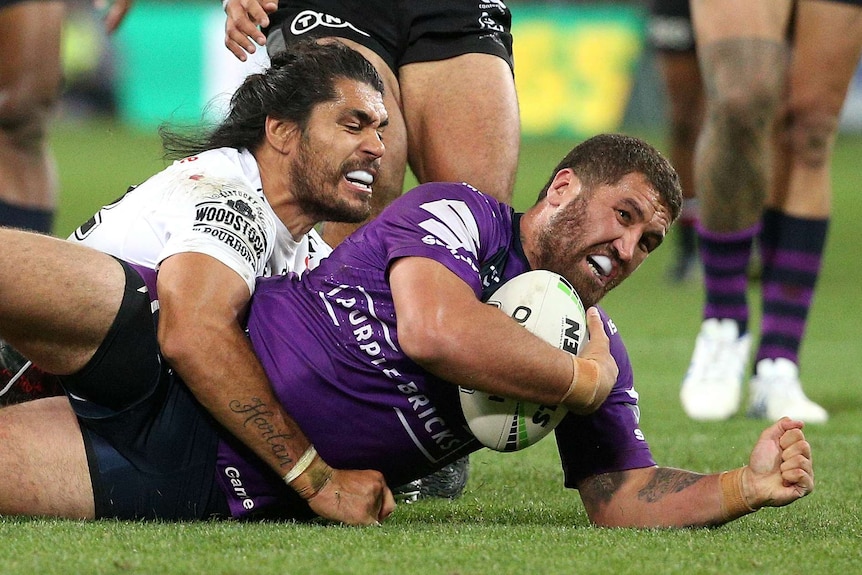 Kenneath Bromwich holds the ball under his arm and is tackled by Tohu Harris