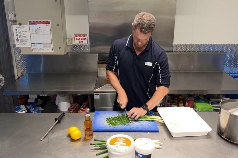 Chef Craig Fitzgerald in his restaurant kitchen chopping shallots. 