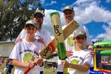 Two men stand behind their two young sons holding cricket bats.