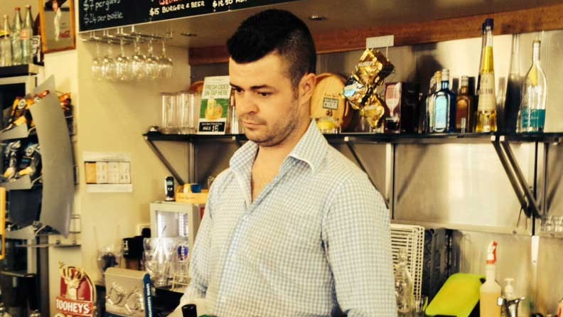 Barman standing at beer taps in pub