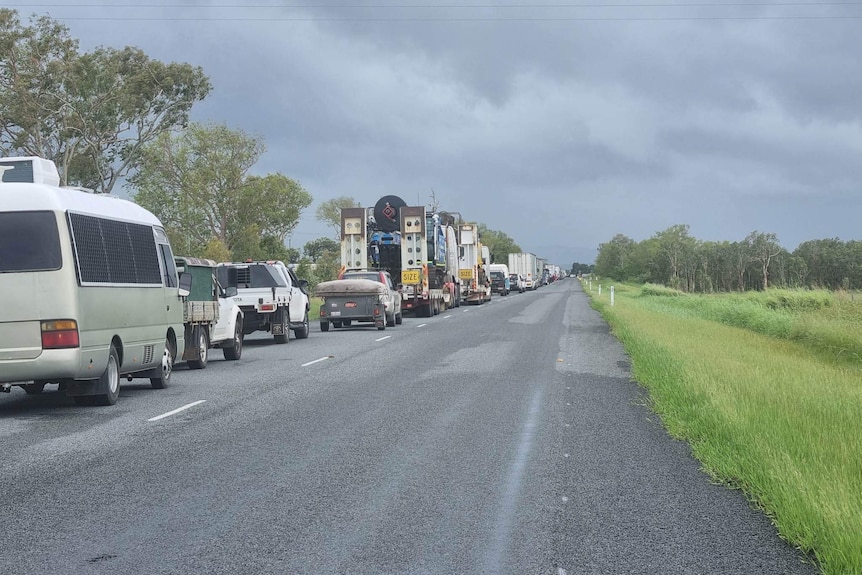 Trucks and cars on the road under a cloudy sky. 