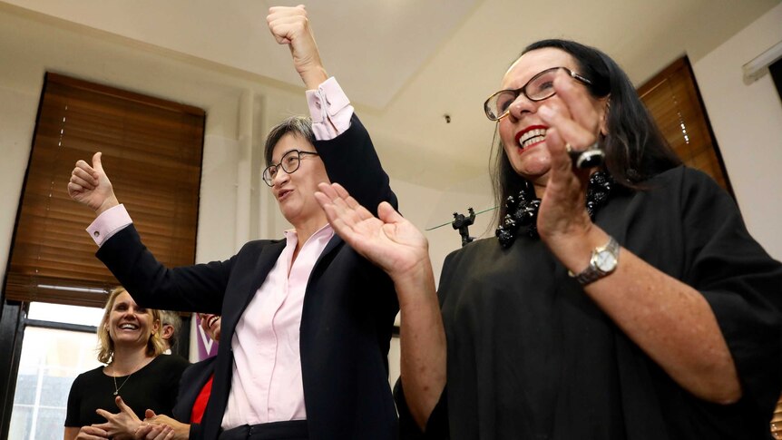 Penny Wong gives two thumbs up to the crown as Linda Burney claps and smiles alongside her