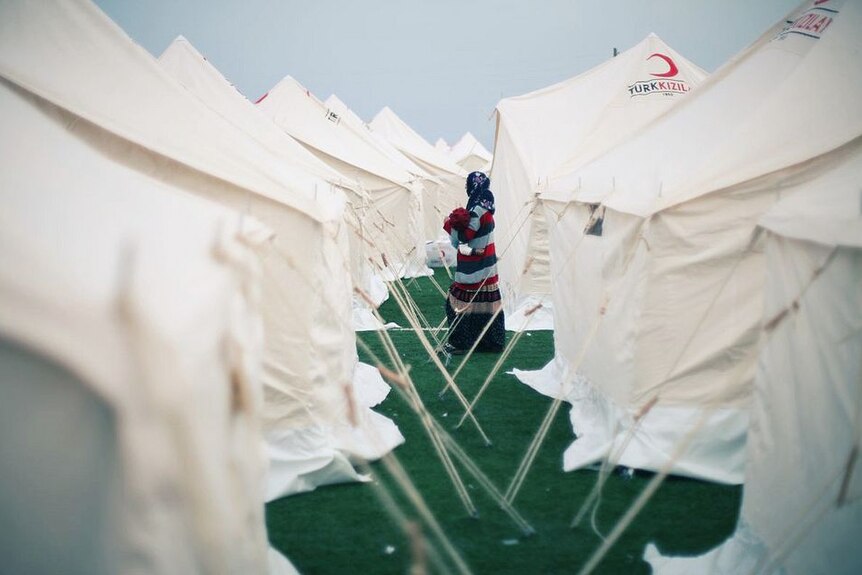 Turkish woman walks between tents