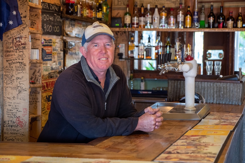 A man wearing a baseball cap leans on the bar at the Tilpa pub