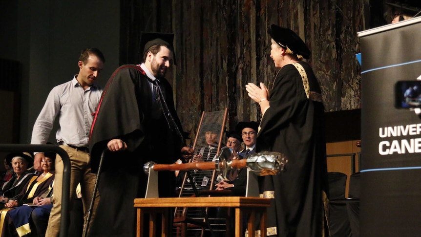 Paul Jenkins walks across the stage to accept his degree.