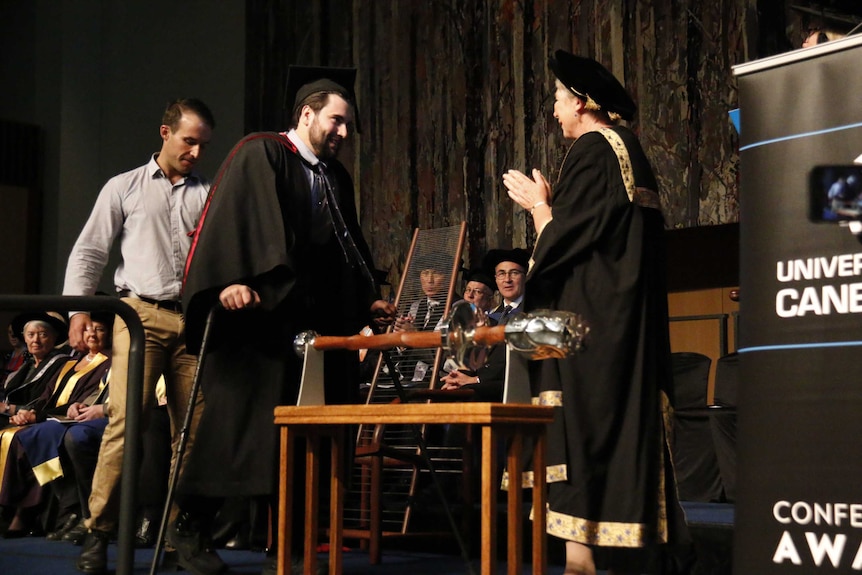 Paul Jenkins walks across the stage to accept his degree.