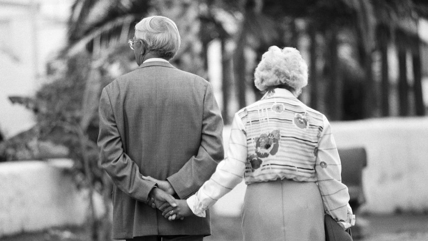 A older couple walk hand in hand.