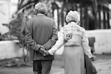 A older couple walk hand in hand.