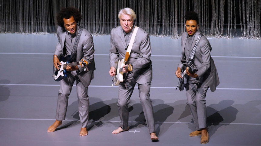 David Byrne, bassist Bobby Wooten and guitarist Angie Swann perform on stage
