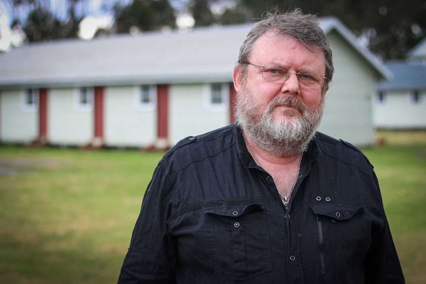 Greg Raue standing outside one of the huts at Bonegilla.