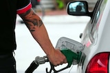 a person's arm is shown pumping petrol into a white car