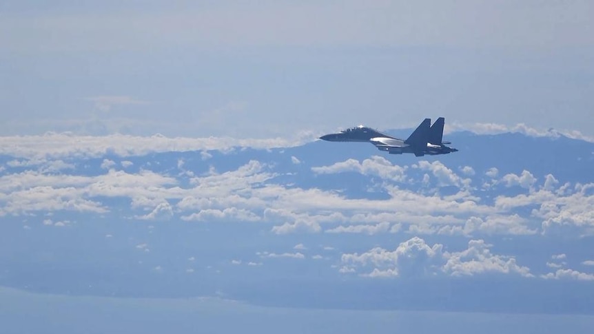 A fighter jet flies above the clouds.