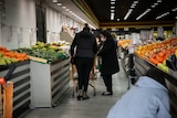 two women pushing a trolley doing shopping at a fuit shop