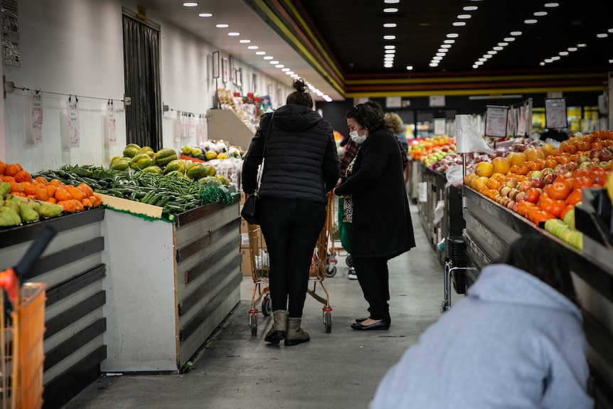 two women pushing a trolley doing shopping at a fuit shop