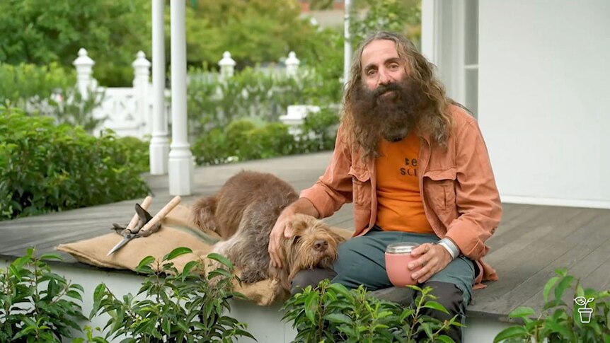 Costa sitting on a verandah with Humphrey the dog.