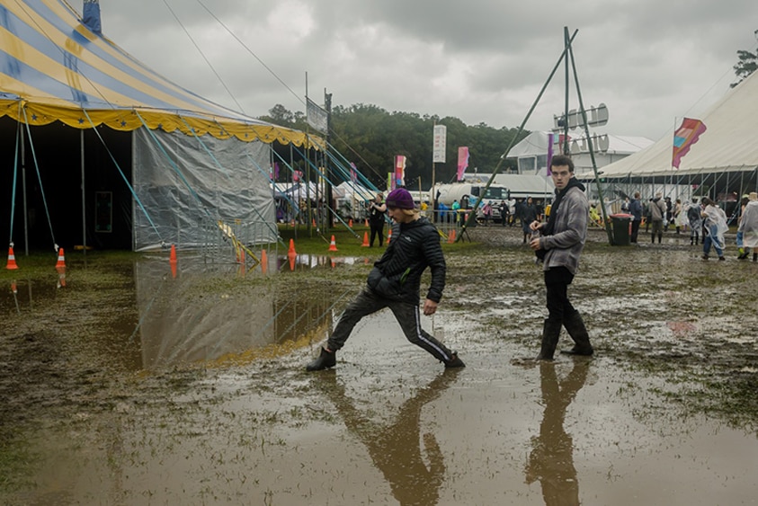 two festival-goers wade through a muddy pool at Splendour In The Grass
