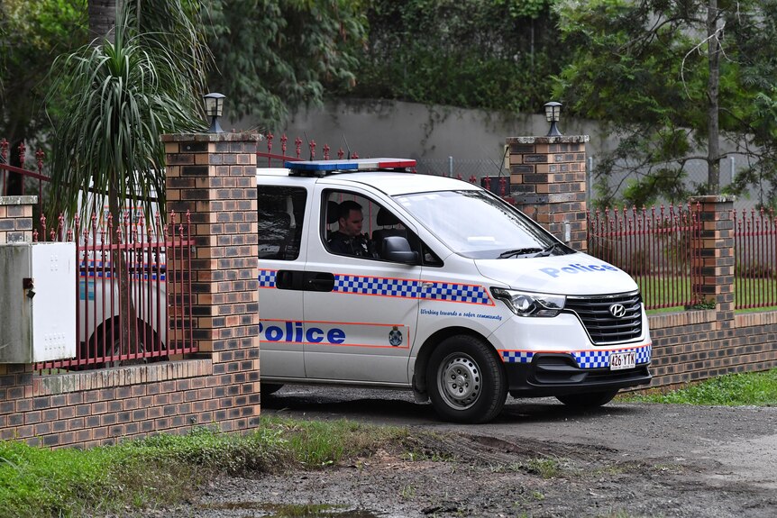 A police car driving through the open gate of a Taigum property.