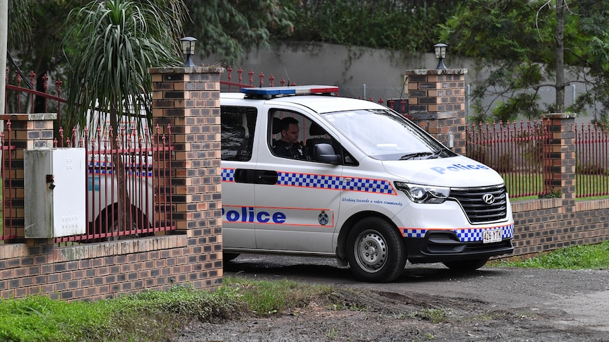 A police car driving through the open gate of a Taigum property.