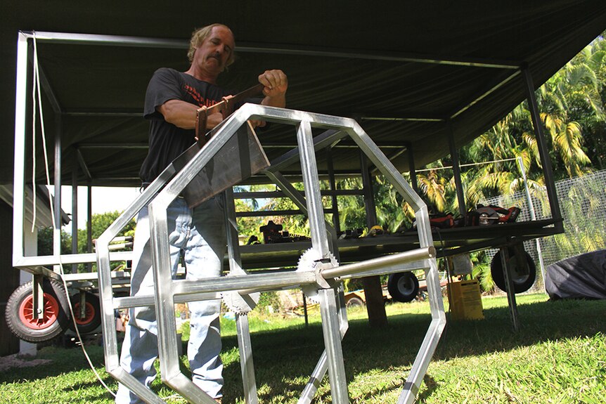 Beer can boat builder Mick Keeley secures clamp on paddle wheel