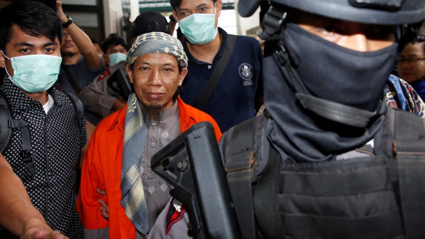 Policemen guard Islamic cleric Aman Abdurrahman during his walk to the courtroom.