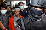 Policemen guard Islamic cleric Aman Abdurrahman during his walk to the courtroom.