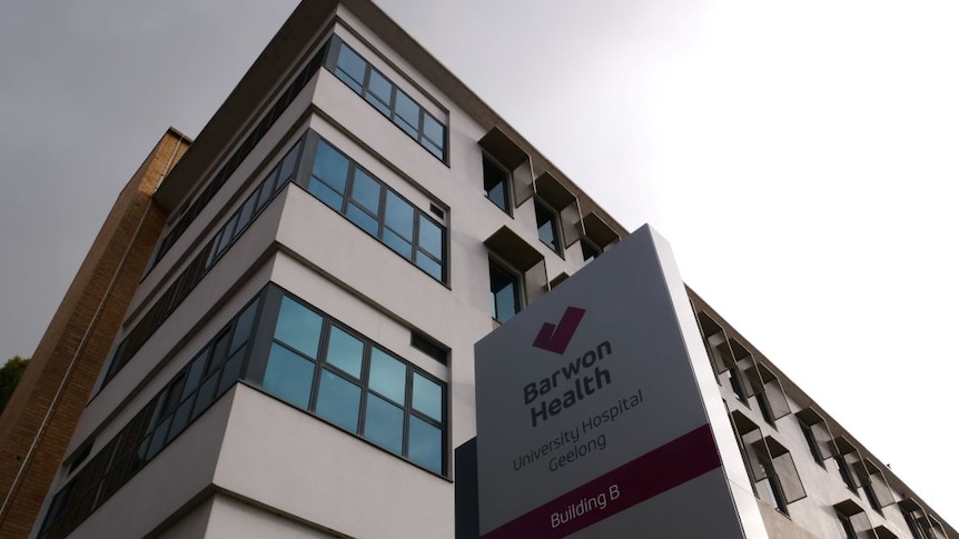 A sign outside a hospital building reads Barwon Health, University Hospital Geelong, Building B.
