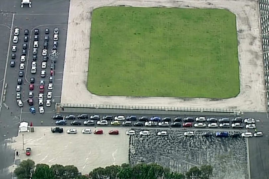 An aerial photo shows lines of cars queued around an oval at a testing site.