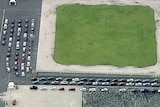 An aerial photo shows lines of cars queued around an oval at a testing site.